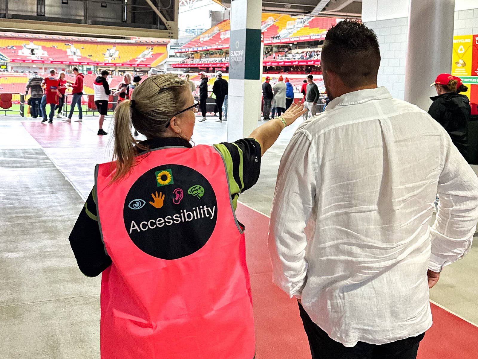 The Suncorp Stadium Accessibility Attendant wearing a bright pink vest helping a patron with directions and navigating the Stadium