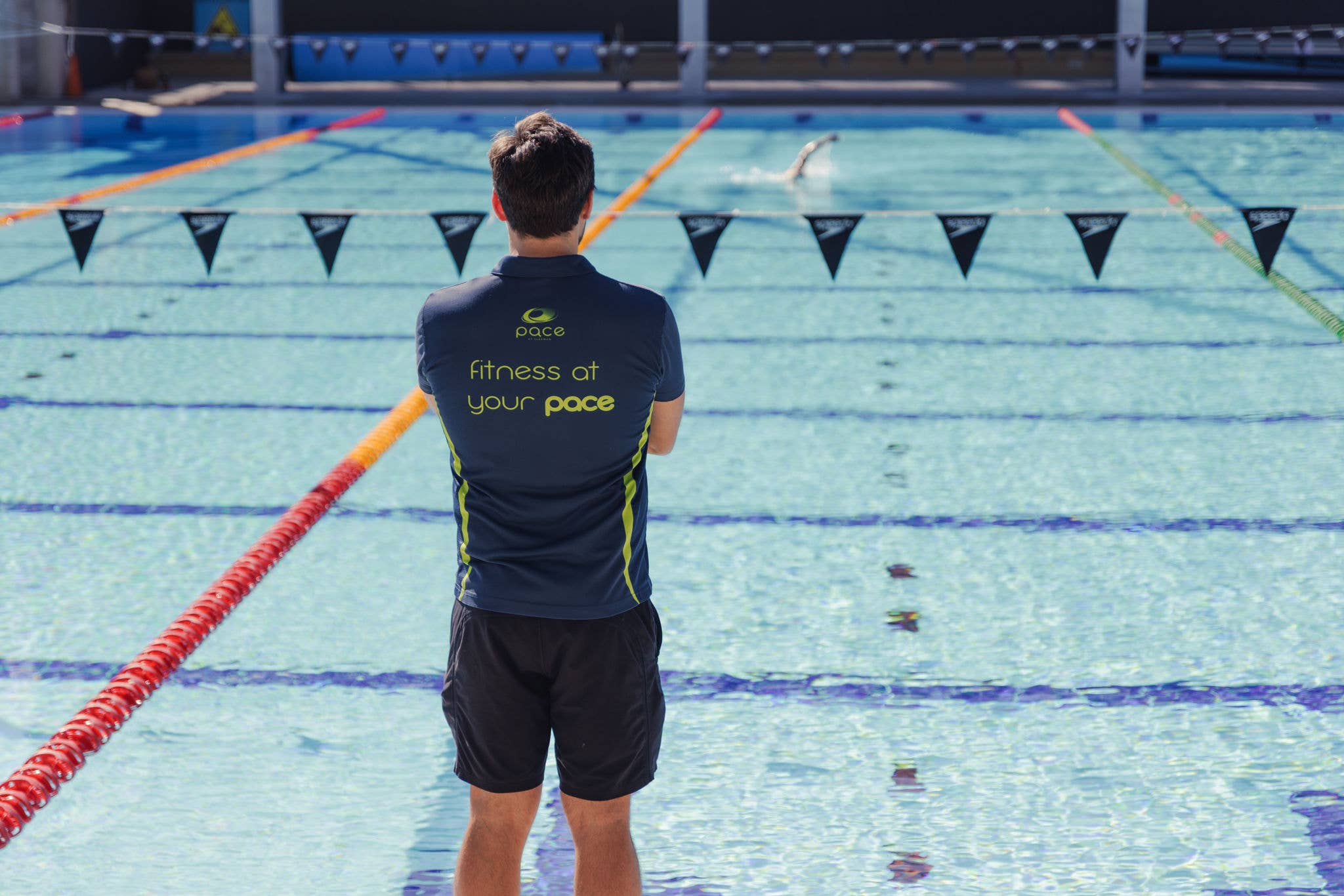 A lifeguard watches over a swimmer in a swimming pool